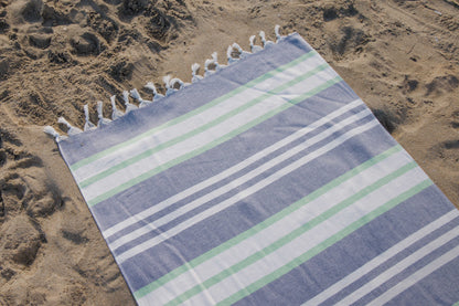 blue and green striped towel laying in the sand