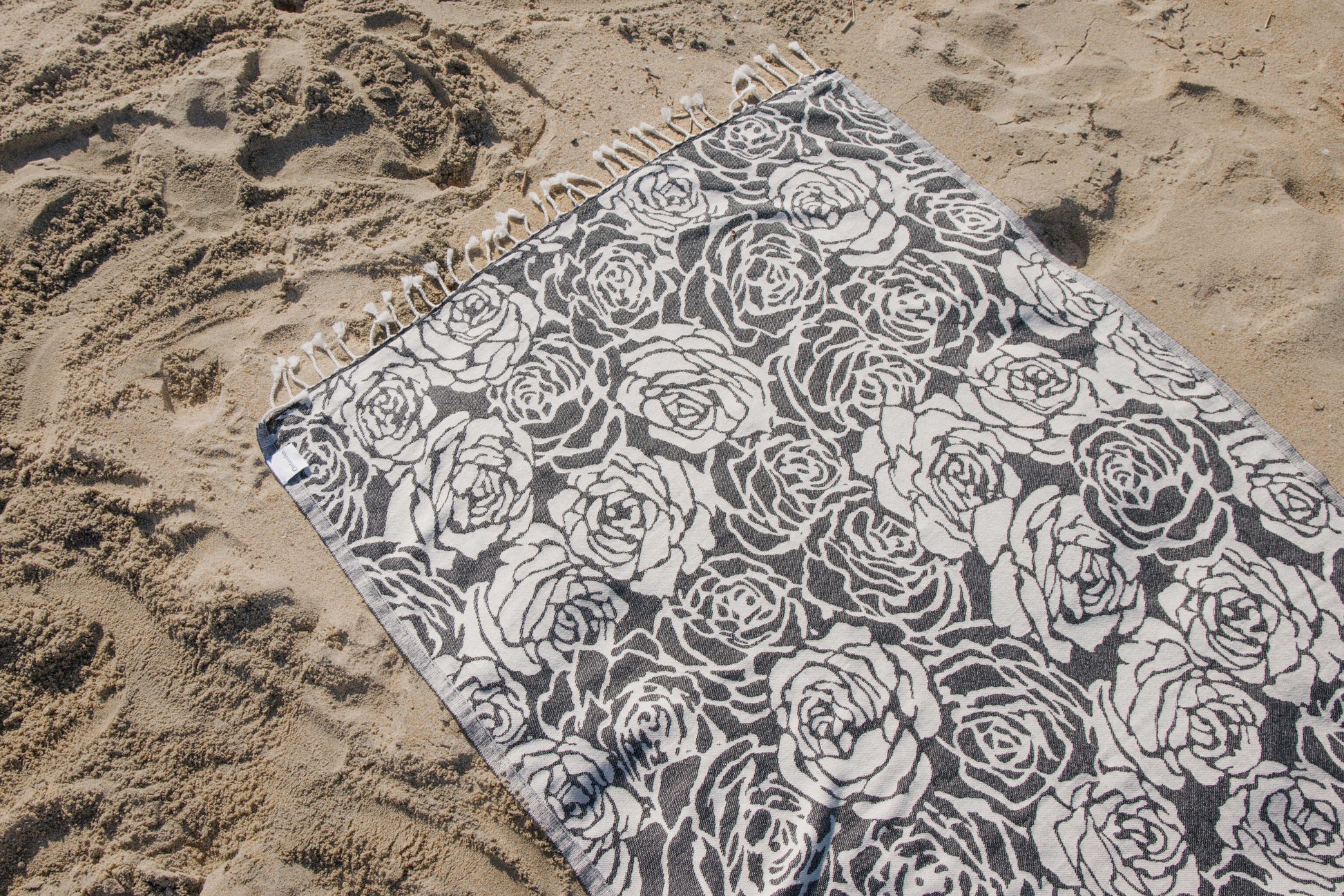 Beach towel with rose pattern on sand