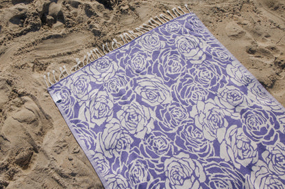purple rose towel laying on the sand on a beach