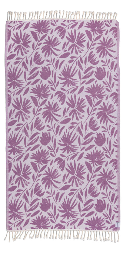 Towel with purple floral pattern and white fringe on a white background