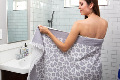 woman in a bathroom wrapped in a grey and white leopard print terry cloth towel
